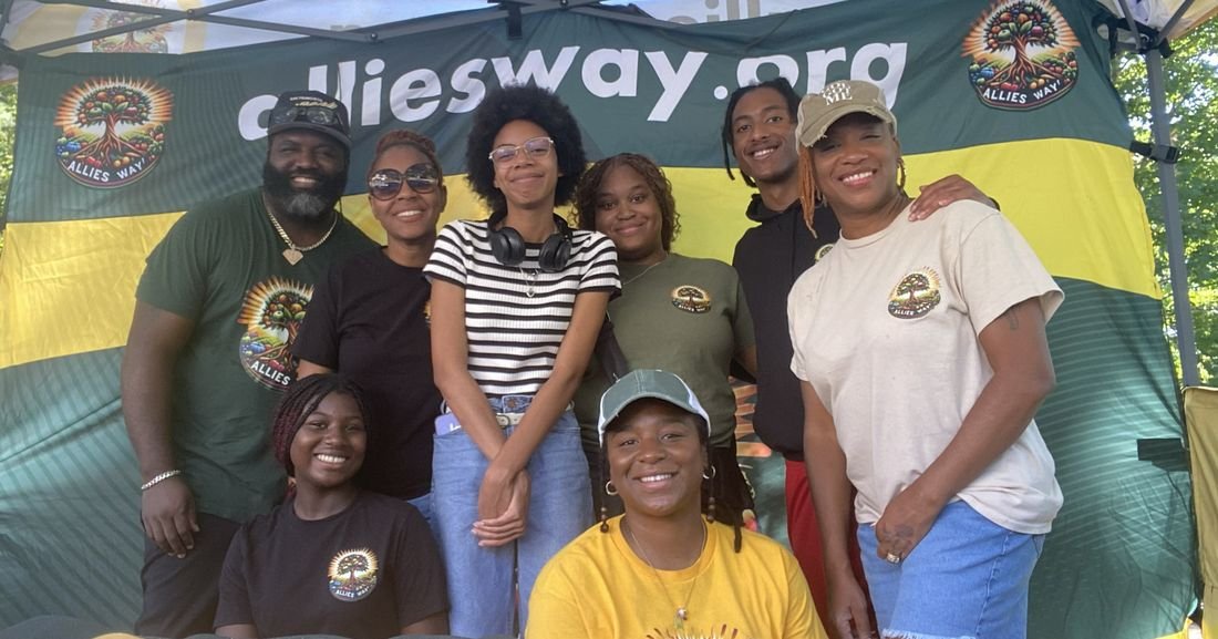 The Allies Way team in front of the alliesway.org banner